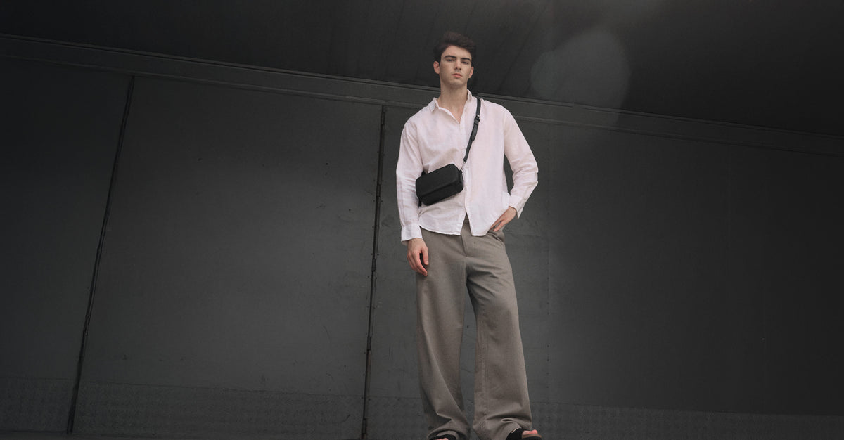 Man with a small AGENTLE crossbody pouch in a concrete room